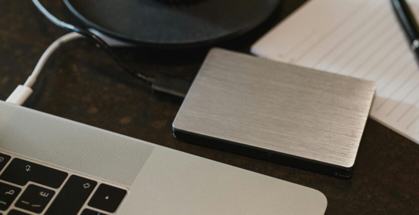 Free Closeup of an external hard drive connected to a laptop with a USB cable on a desk. Stock Photo