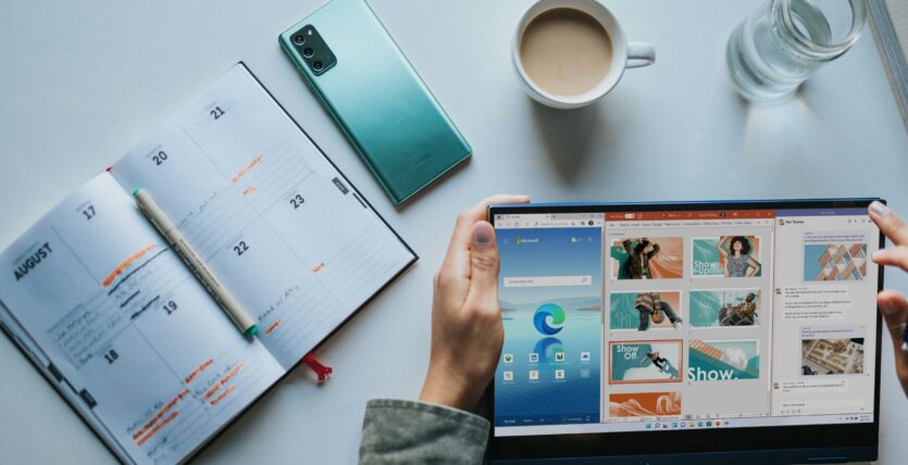 person using Windows 11 computer beside white ceramic mug on white table