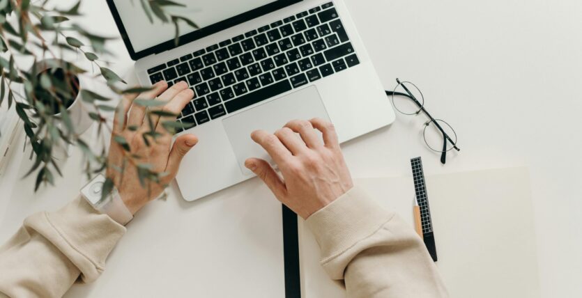 Free An overhead view of a person working on a laptop in a minimalist home office setting. Stock Photo