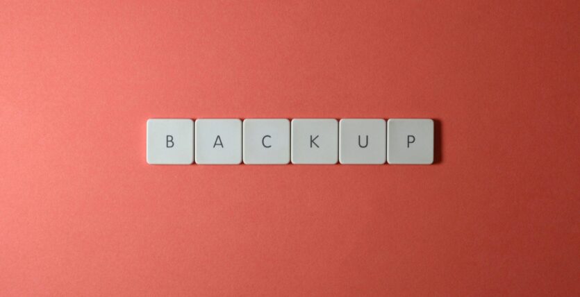 Free Close-up of keyboard keys spelling 'BACKUP' placed on a coral-colored surface. Stock Photo
