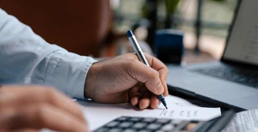 Free A person calculating finances with a calculator and pen on a desk indoors. Stock Photo