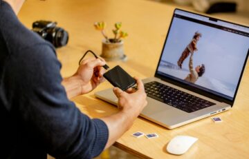 A man sitting at a table with a laptop and cell phone